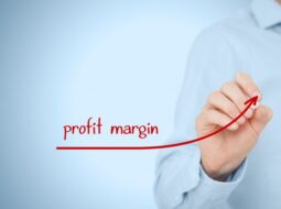 Person drawing an upward red arrow labeled “profit margin” on a transparent screen, symbolizing increasing operating margin and strategic financial performance.