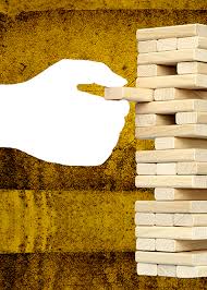 an in progress jenga game showing how all of the pieces are built upon each other. A hand starts to put on one piece watching to see if the stack falls,,, creating imagery of the assumption stack.