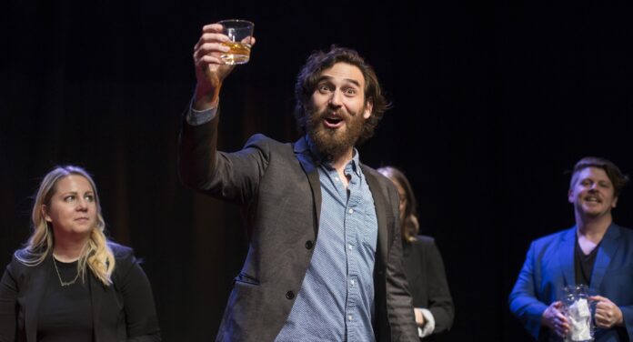a man presenting at a meeting on a stage with a cocktail in his hand signifying forecast theater