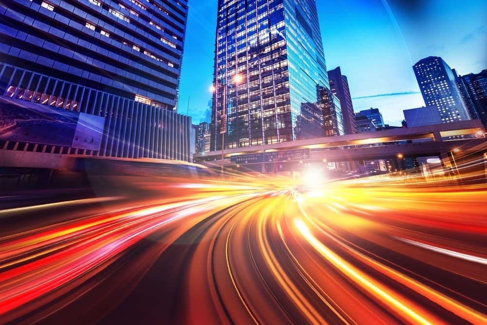 City scape at night where street and car lights are stretched through time to represent organizational speed